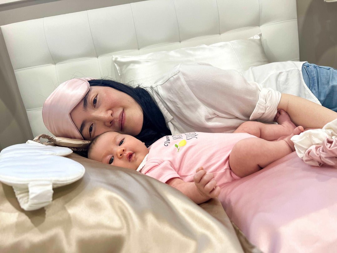 A woman and a baby lying on a bed adorned with Champagne Moon Flower silk bedding