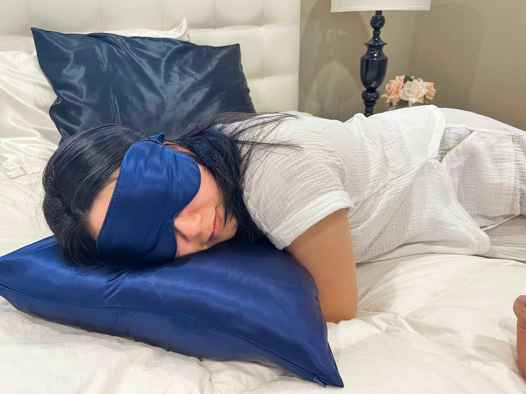 Sleeping woman with a navy blue silk sleep mask in a cozy bed