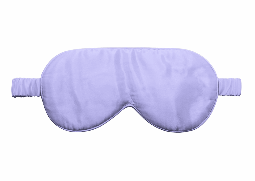 Lilac silk sleep mask with elastic band displayed on a neutral surface