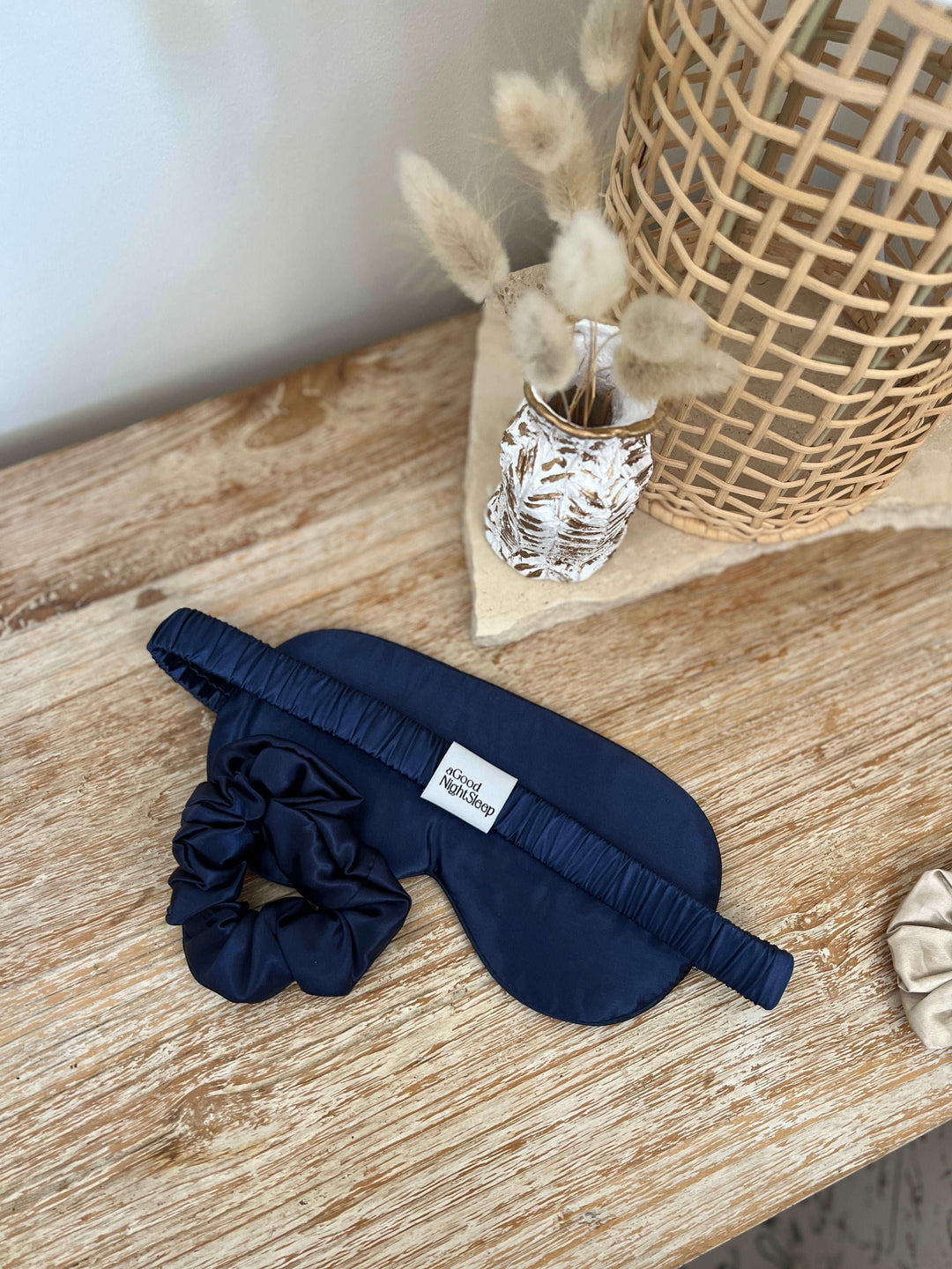Navy blue silk hair scrunchie placed on a wooden surface