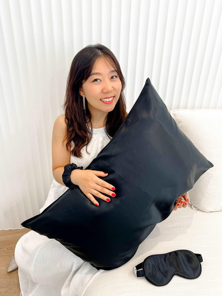 A woman comfortably lounging on a sofa, displaying the luxurious black silk pillowcase