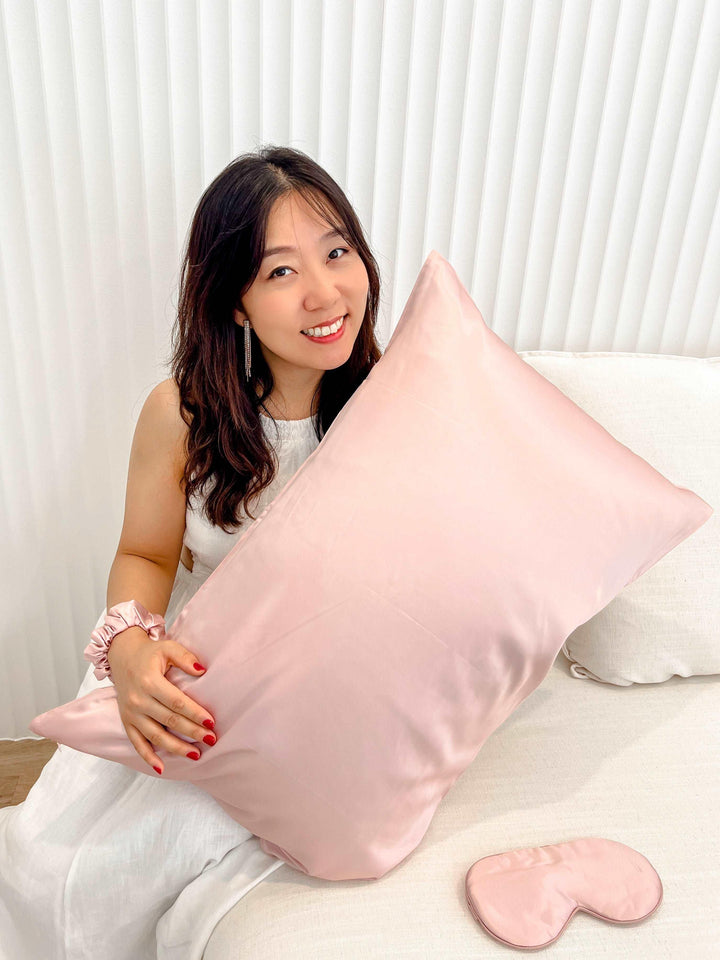 Woman reclining on a bed showcasing the Pink Queen silk pillowcase