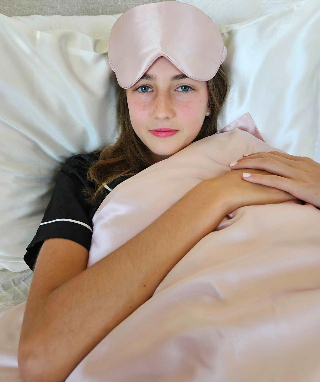 Pink Queen silk pillowcase with coordinating eye mask on a bed