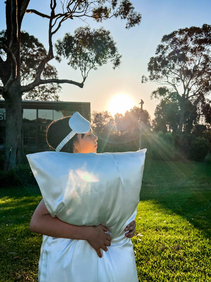 White Moon Flower silk pillow held by a woman in natural sunlight