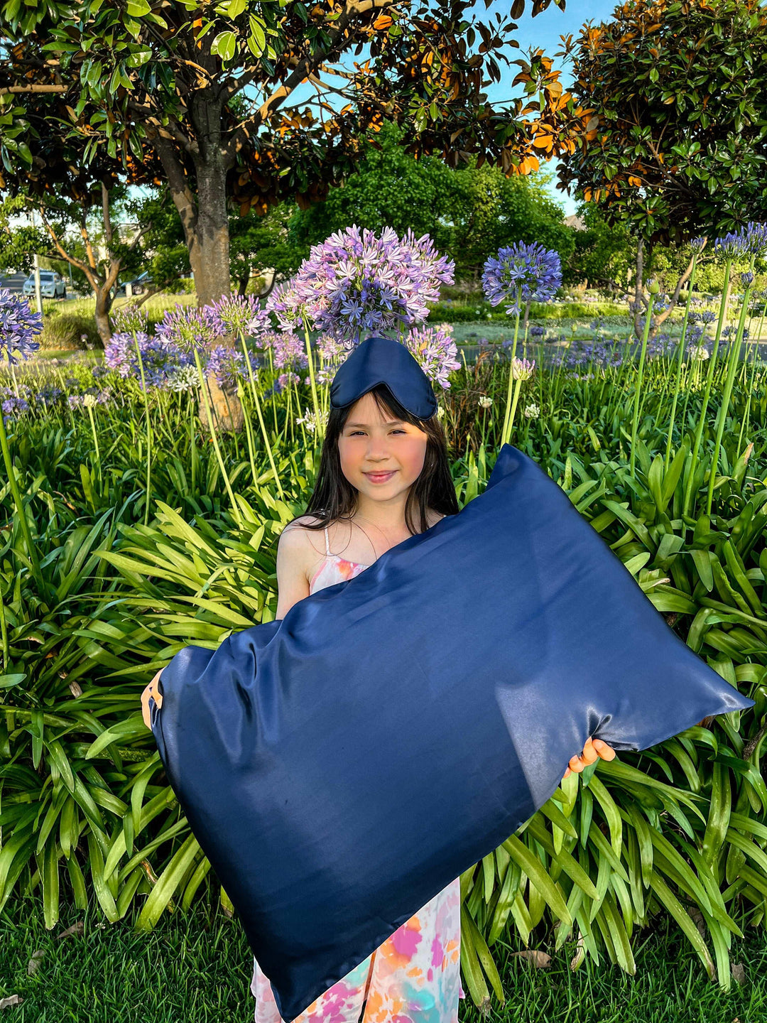 Young girl happily holding the navy blue silk pillow from the gift set