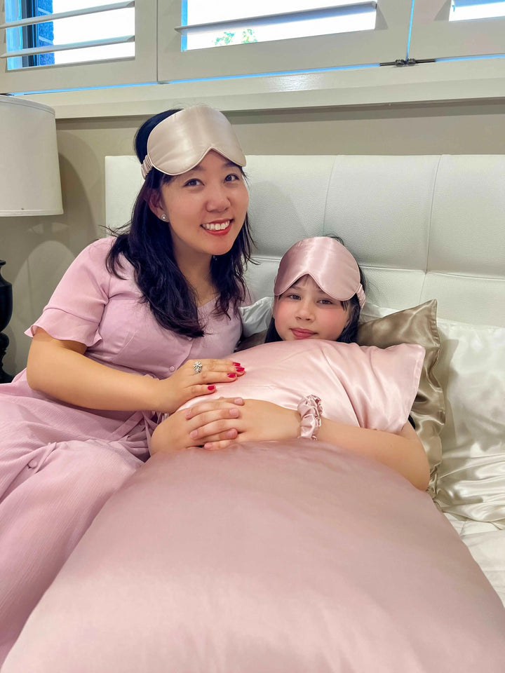 Friends wearing pink sleepwear and using Pink Queen silk pillowcases during a sleepover