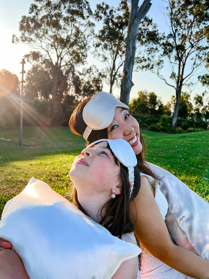 A peaceful outdoor setting with individuals lounging in white attire and silk sleep masks 