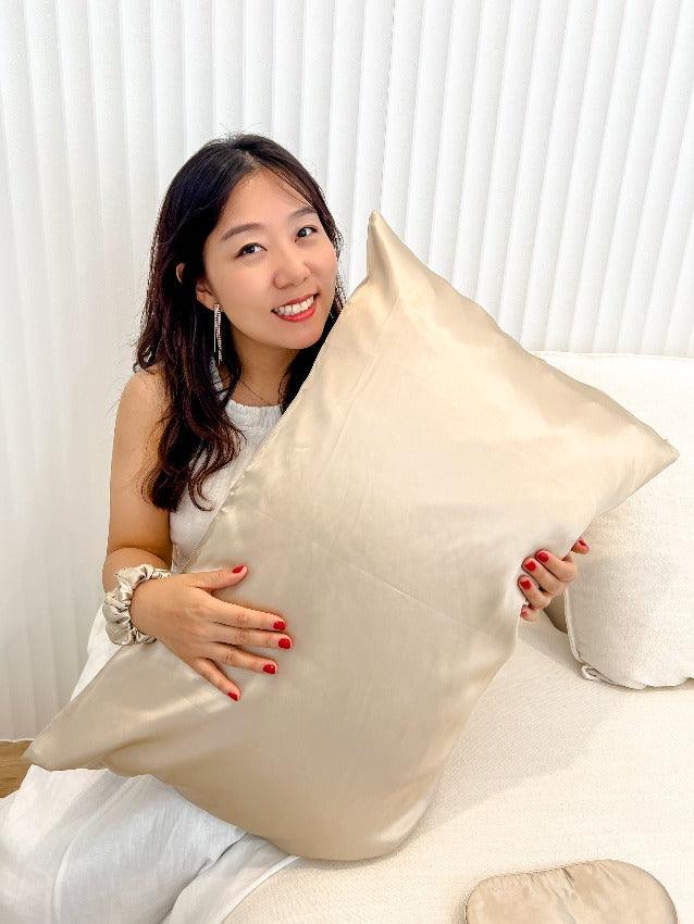 A woman holding a silk pillowcase from the Champagne Moon Flower gift set