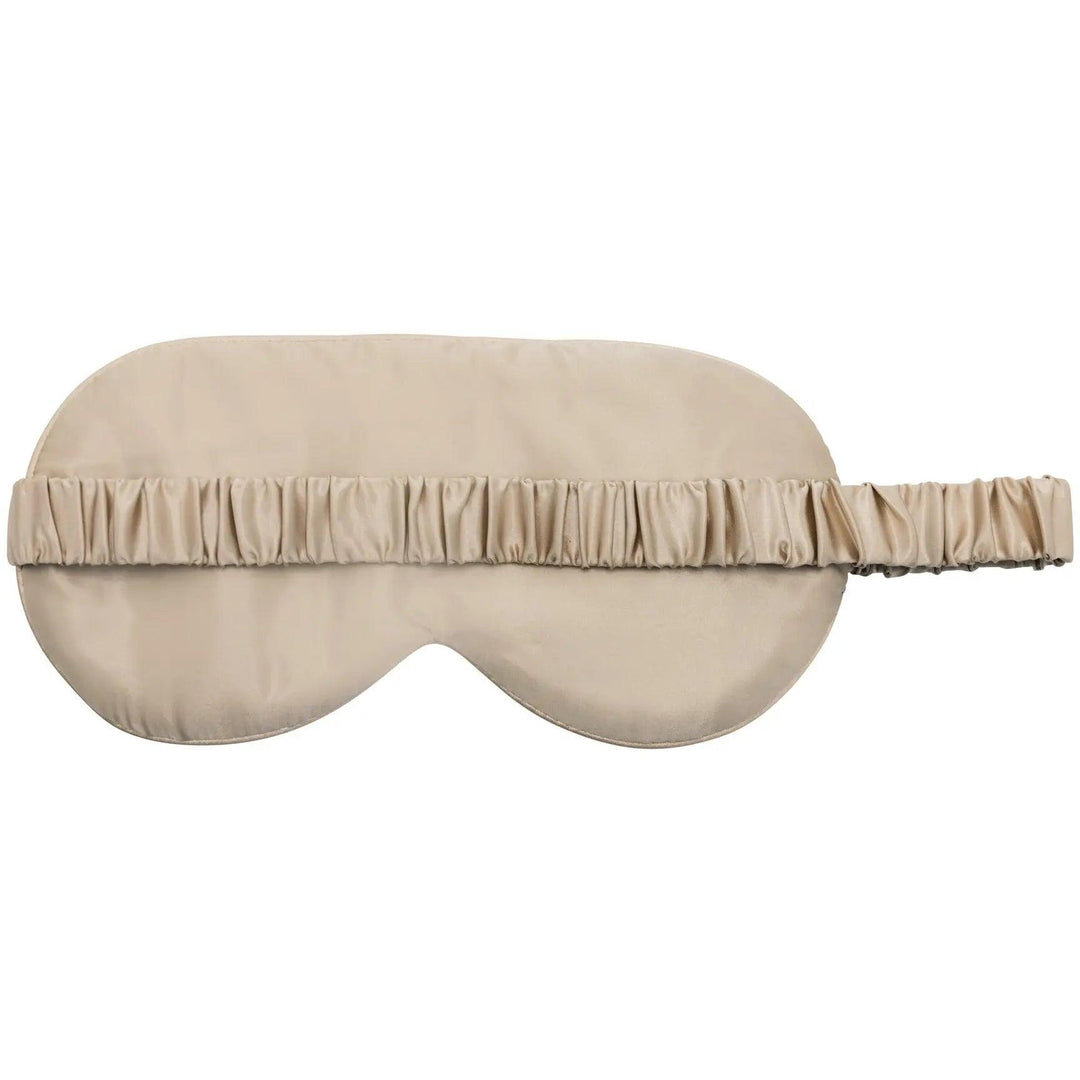 Close-up of a champagne silk sleep mask with delicate ruffles